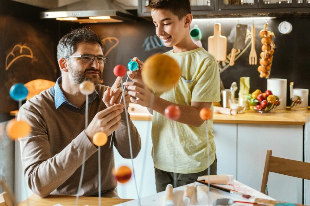 a kid and a parent building a solar system at home